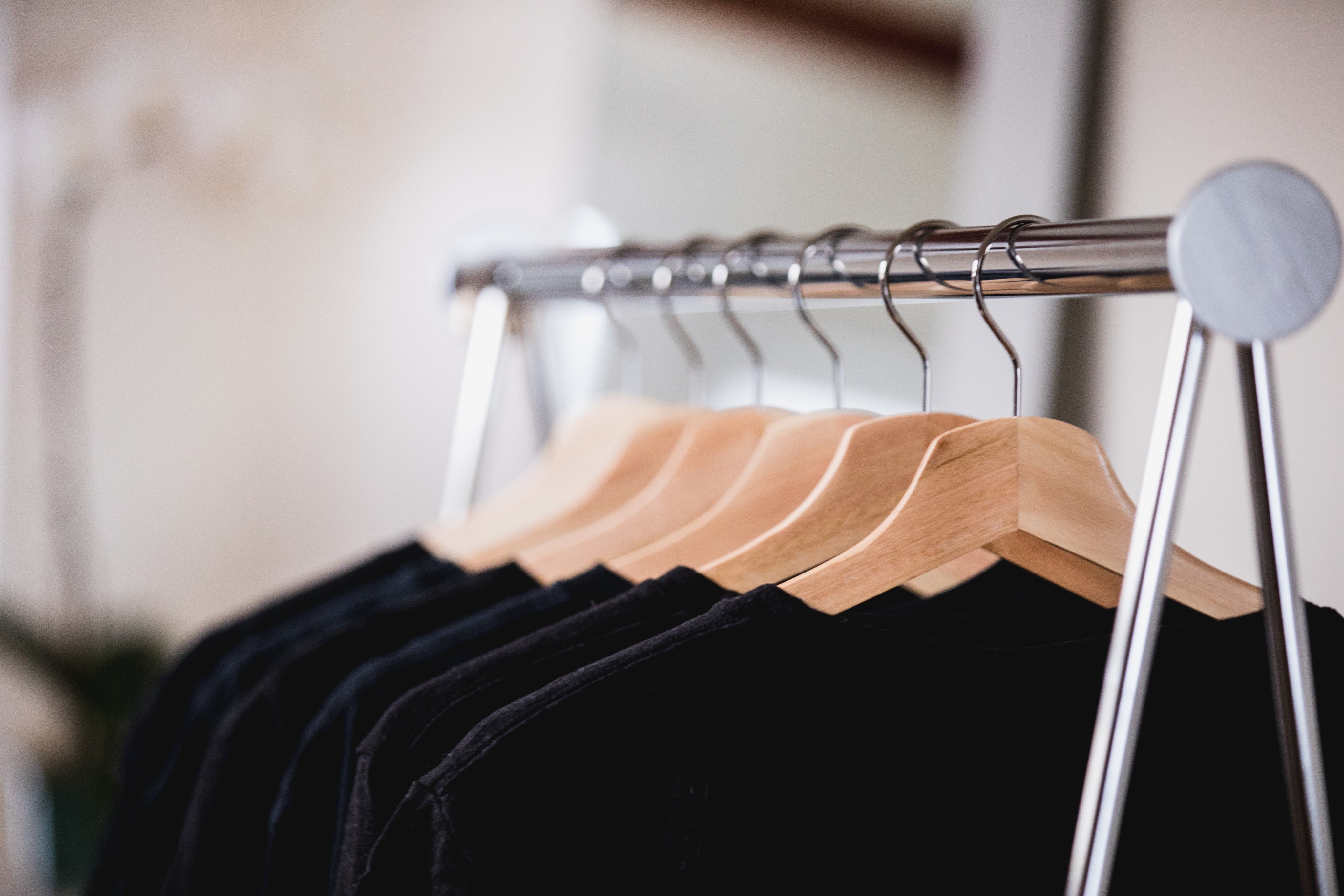 Sort og blåt tøj på et stativ i en solbelyst butik